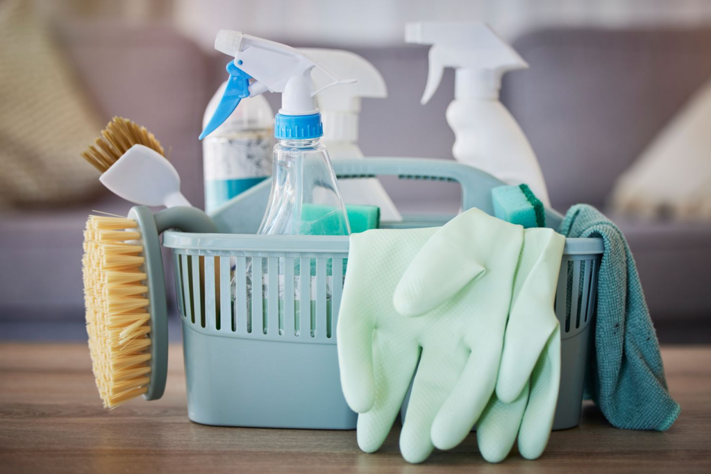 Cleaning caddy with spray bottles, scrub brush, sponges, and rubber gloves for safe dead rat cleanup