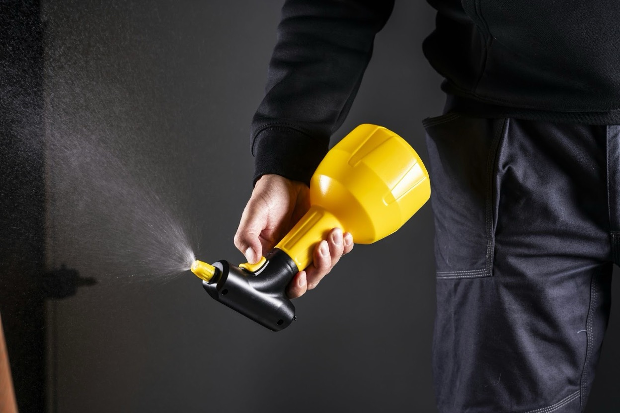 A man spraying a pest control solution inside a house