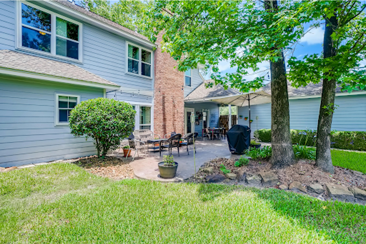 Shaded backyard patio with wicker seating and lawn protected by mosquito control measures