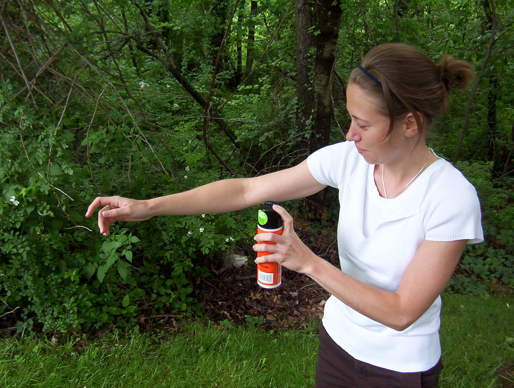 Woman applying EPA-registered insect repellent to her arm outdoors for mosquito protection. (Source)