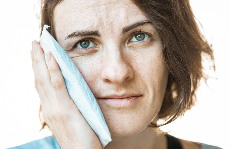 A person holding a cold compress against their skin to reduce the swelling caused by a cockroach bite.